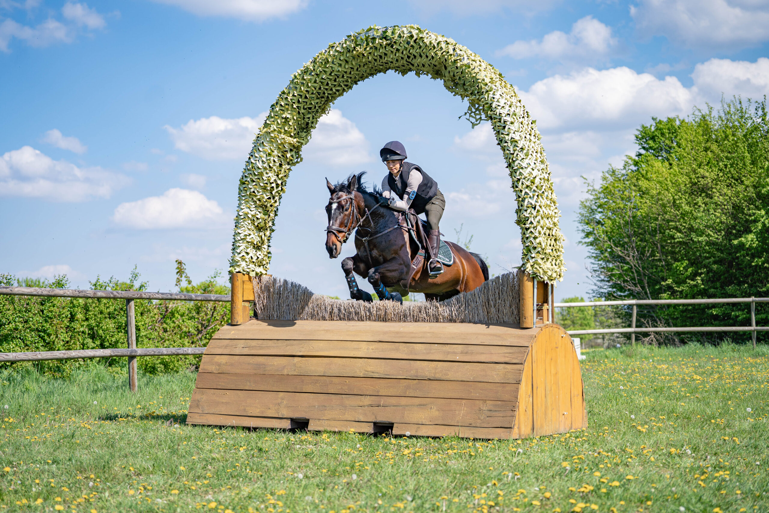 Springreiterin springt mit ihrem Pferd durch ein Nadelör