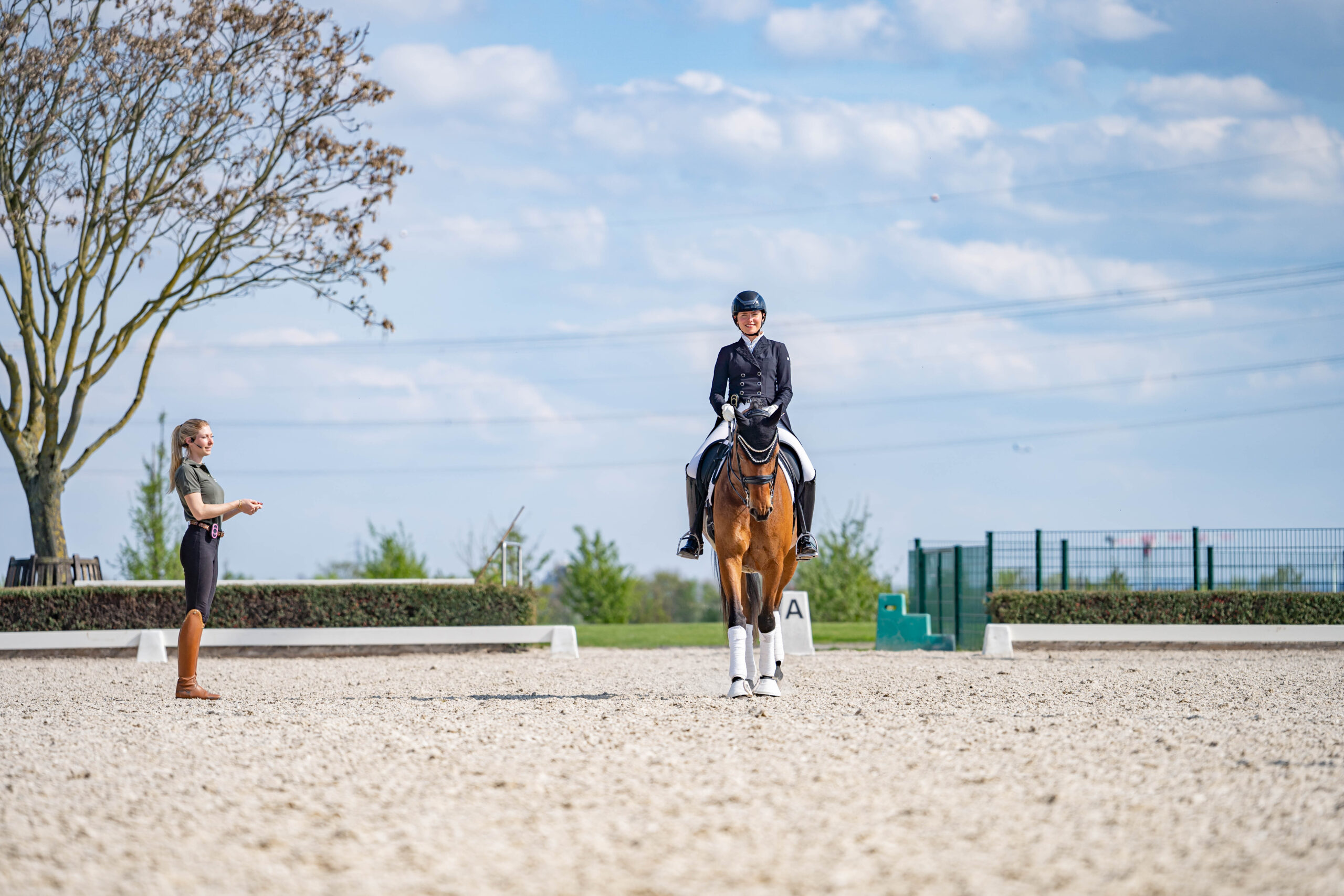 Reitlehrerin gibt Dressurreiterin die auf Mittellinie mit ihrem Pferd reitet Reitunterricht